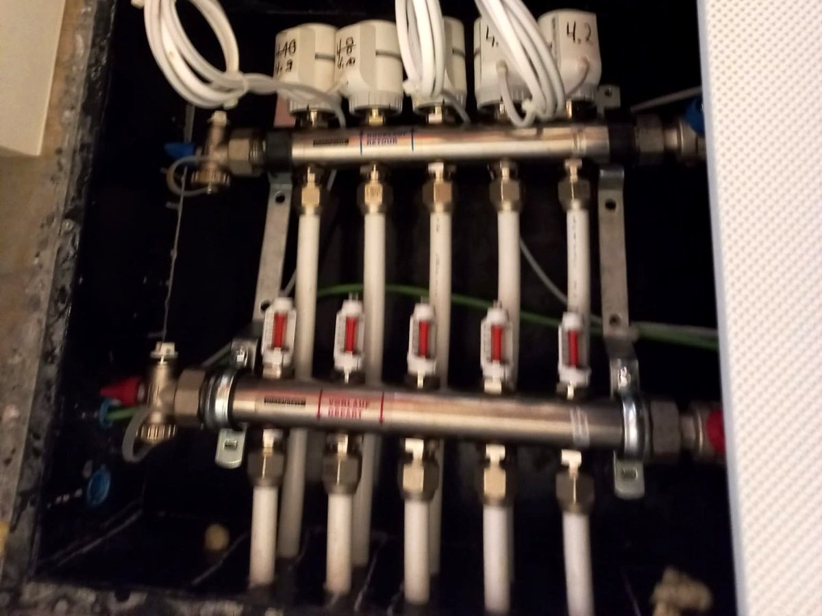 Un collecteur de dalle active, dans le faux plafond d’un couloir : têtes électriques en haut, débitmètres en bas. Ici tout circulait — et pourtant rien ne rafraîchissait.